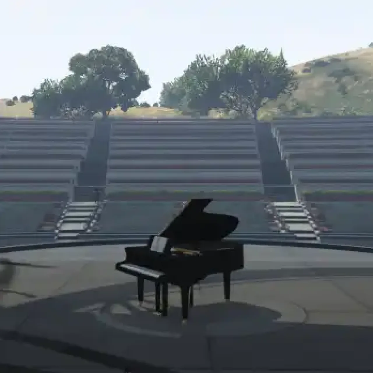 Grand piano on an outdoor amphitheater stage in a scenic setting.